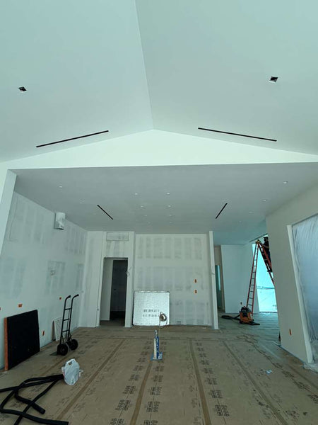 New build room with ladders, tools, unfinished drywall, and a Cryptic Air Pro Mud-In Linear Slot Diffuser.